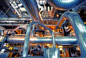 Equipment, cables and piping as found inside of a modern industrial power plant. Industrial zone, Steel pipelines, valves, cables and walkways