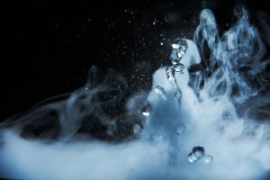 Boiling water splash with steam on black background closeup.