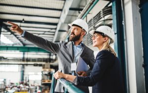 A portrait of a mature industrial man and woman engineer with tablet in a factory, working.