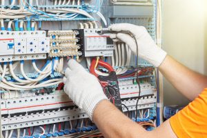 A closeup of an electrical engineer working in a power electrical panel in a factory or apartment building. Check the parameters of the power plant.