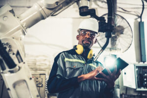 African American factory worker working with adept robotic arm in a workshop . Industry robot programming software for automated manufacturing technology .